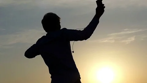 Young Man is Dancing With Earbuds in Hands at Sunset in Slow Motion. Stock Footage
