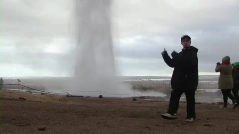 Young man dancing in front of erupting geysir in Iceland Stock Footage 259720275