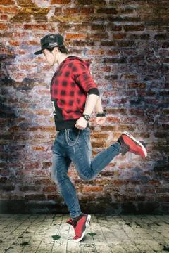 Young man dancing in front of an old brick wall and floor tiles. Modern dance Stock Photos
