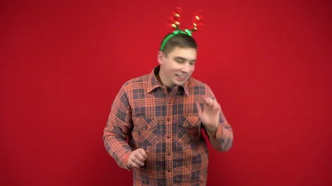 A young man is dancing with a headband in the form of Christmas antlers. Studio Stock-Footage 143932425