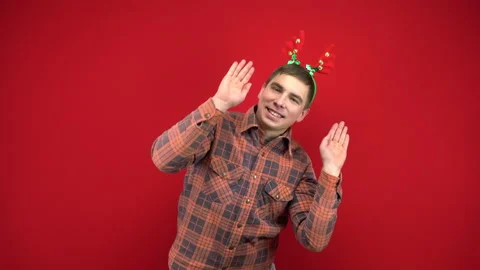 A young man is dancing with a headband in the form of Christmas antlers. Studio Stock Footage 143932531