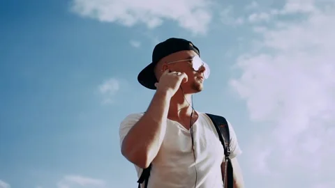 Young man dancing with headphones on the sky background 库存影片 94974811