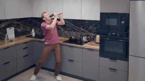 Young man dancing in the kitchen singing to the scoop Stock Footage 164311495