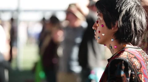 Young man dancing with multi-colored gems stuck on face at festival Stock Footage 51230662