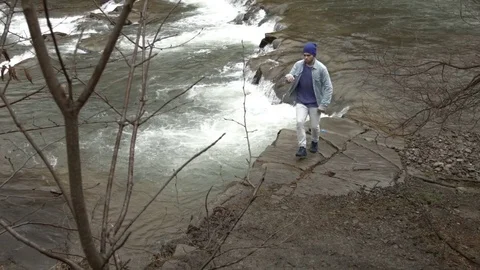 Young man dancing near a river in the mountains 스톡 동영상 82607312