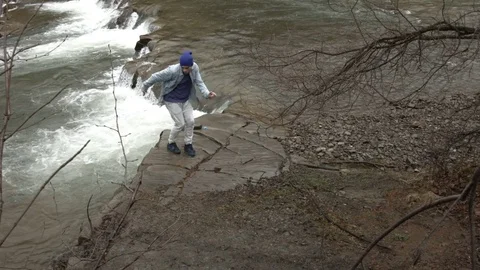 Young man dancing near a river in the mountains Vídeo Stock 82608116