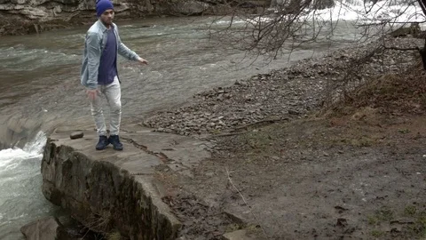 Young man dancing near a river in the mountains 스톡 동영상 82609538