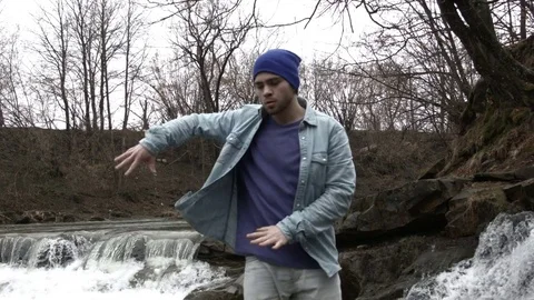 Young man dancing near a river in the mountains Video stock 82616768