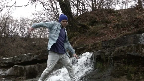 Young man dancing near a river in the mountains Stock Footage 82617874