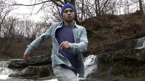 Young man dancing near a river in the mountains 스톡 동영상 82623853