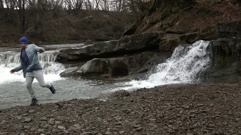 Young man dancing near a river in the mountains 動画素材 82629034