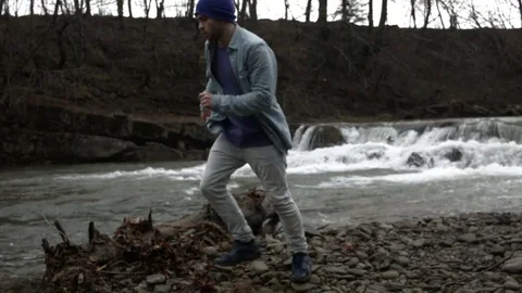Young man dancing near a river in the mountains Video stock 82630995