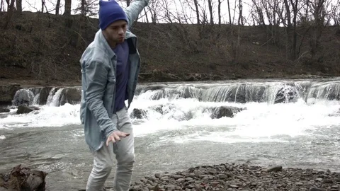 Young man dancing near a river in the mountains Vídeos de archivo 82631573