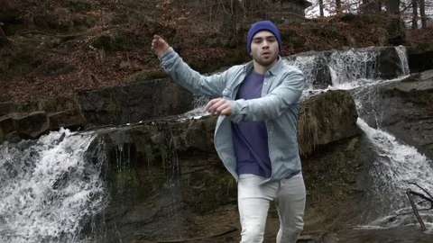 Young man dancing near a river in the mountains Video stock 82631977
