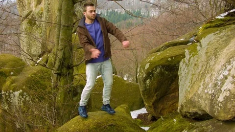Young man dancing on a rock Видео 81164159