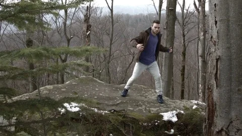Young man dancing on a rock in the mountains. 動画素材 82688884