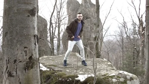 Young man dancing on a rock in the mountains. Vídeos de archivo 82690382