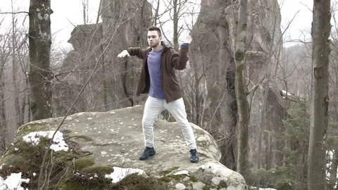Young man dancing on a rock in the mountains. Video stock 82694868