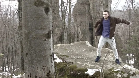 Young man dancing on a rock in the mountains. Vidéo 82697745