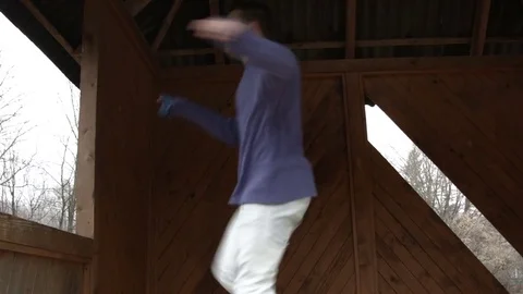 Young man dancing on a wooden bus stop 스톡 동영상 82591332