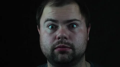 Young man on dark background surprised looking at the camera Stock Footage 130216955