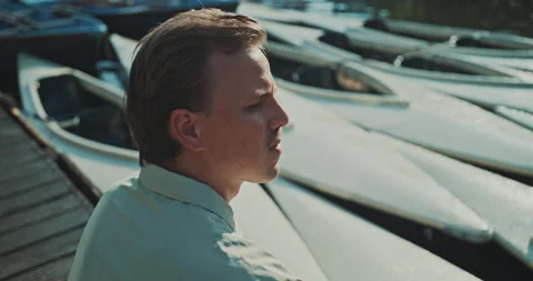 Young man daydreaming while sitting on the dock Stock Footage 221317632