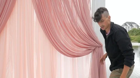Young man decorates a festive arch of pink fabric Stock Footage 83273845