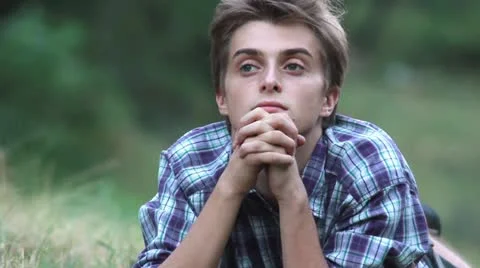 Young man deep into his thoughts laying on the grass. Video stock 11895330