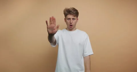 Young man demonstrates various hand gestures in a studio setting with a pla.. Stock Footage 317328041