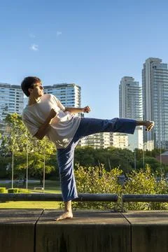 Young man demonstrating a powerful kick in an urban setting Stock Photos