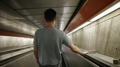 Young man descending escalator in underground passage Stock Footage 332781767