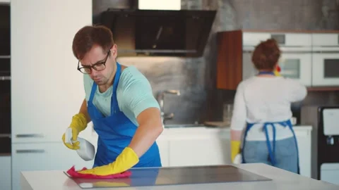 Young man with detergent spray and cloth cleaning cooking top when woman wiping Stock Footage 140328807