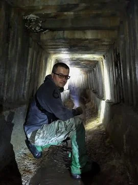 A young man, a digger, sat down in the tunnel of the sewage collector Stock Photos