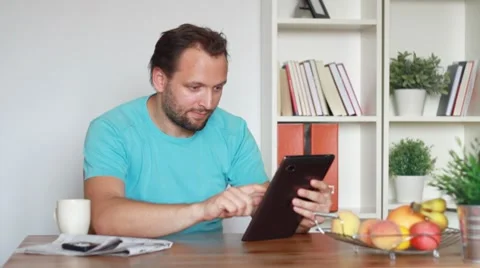 Young man with digital tablet drinking coffee, tea HD Stock Footage 8606970