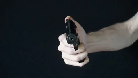 The young man directs at the camera with a black gun and tries to shoot Stock Footage 77067989