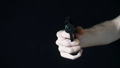 The young man directs at the camera with a black gun and tries to shoot Video stock 77071676