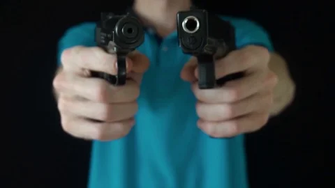 The young man directs two black gun at the camera Video stock 77081395