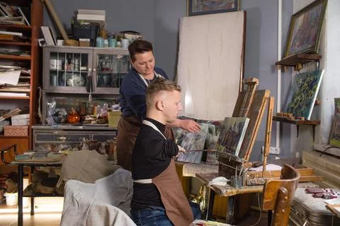 A young man with disabilities is engaged in drawing with a teacher in an art  Stock Photos