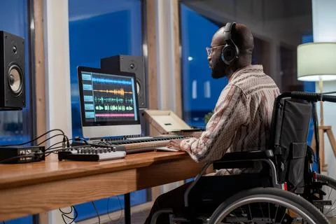 Young man with disability looking at computer screen with sound visualization Stock Photos
