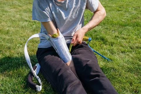 Young man with disability puts on prosthesis in yard Stock Photos