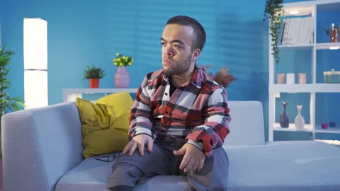 Young man with disabled dwarfism sitting on the sofa at home becomes angry  Stock Footage 230974482