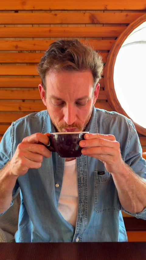 Young man disgust after tasting a cup of coffee, making a grimacing facial Stock Footage 339197037