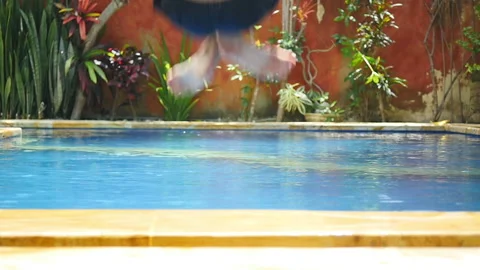 Young man dive bombs into sunny blue pool Stock Footage 132046507