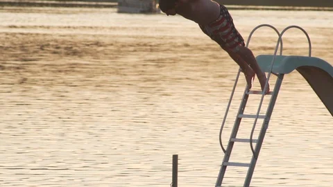 Young Man Dives off Floating Platform during a Beautiful Evening Stock Footage 87043094