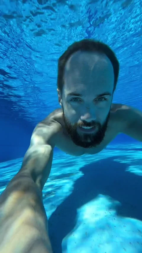 Young man dives into the pool and swims underwater Stock Footage 247984906