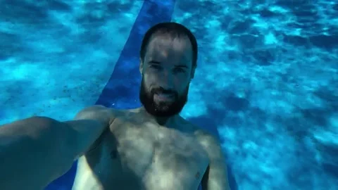 Young man dives into the pool and swims underwater Stock Footage 247984913