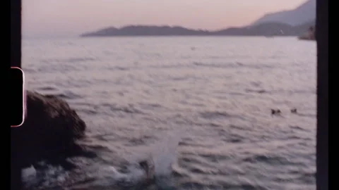 Young man diving into calm ocean at sunset from a rock Stock Footage 307602086