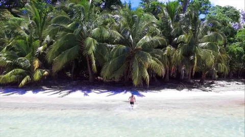 Young man diving into crystal clear waters from the white sand of the beach Stock Footage 89704285