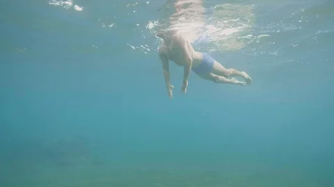 Young man is diving underwater in ocean, side view. Video stock 107136743