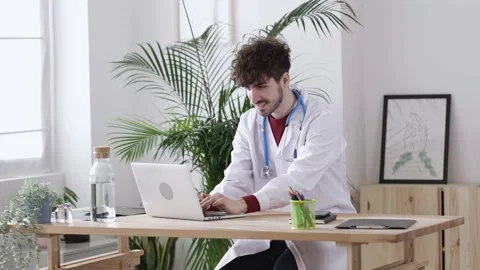 Young man doctor working on personal laptop at his medical office Stock Footage 169978053